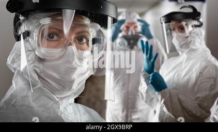Team of Female and Male Doctors or Nurses Wearing Personal Protective Equiment In Hospital Hallway. Stock Photo