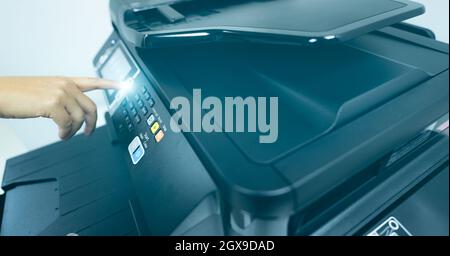 Office worker hand press button on multifunction laser printer. Copy, print, scan, and fax machine in office. Modern print technology.  Photocopy mach Stock Photo