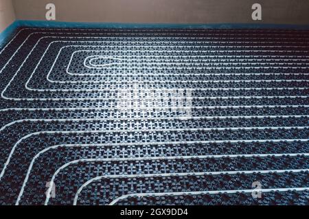 Pipes for underfloor heating ready to be covered with grout on the floor Stock Photo