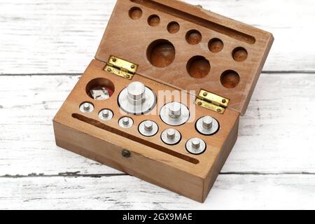 Set of metal weights for scales on the white wooden table Stock Photo