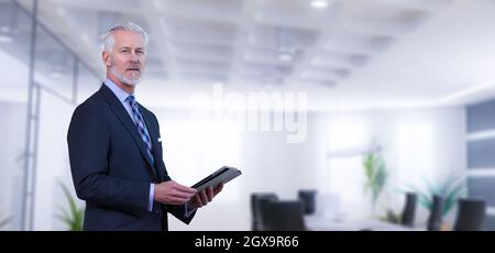 Portrait of senior businessman using tablet in front of his modern office Stock Photo