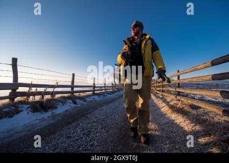 young photographer enjoying beautiful nature while walking on country road during sunny winter day Stock Photo