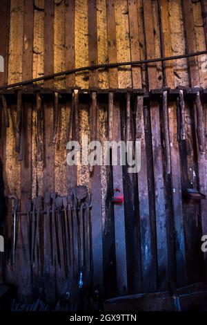 blacksmith tools hanging on a wooden wall Stock Photo