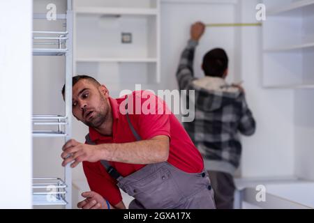 two professional workers installing a new stylish modern kitchen furniture Stock Photo