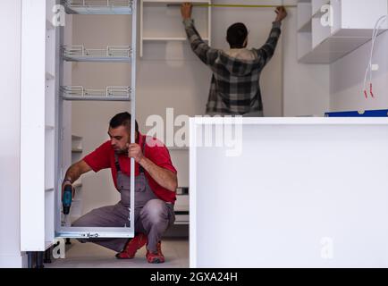 two professional workers installing a new stylish modern kitchen furniture Stock Photo