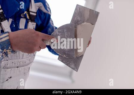 young professional construction worker plastering on gypsum walls inside the new big modern two levels apartment Stock Photo