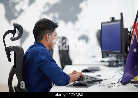 casual indian business man working on desktop computer in modern open plan startup office interior Stock Photo