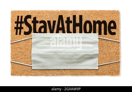 Welcome Mat With Medical Face Mask and #Stay At Home Text Isolated on White Amidst The Coronavirus Pandemic. Stock Photo