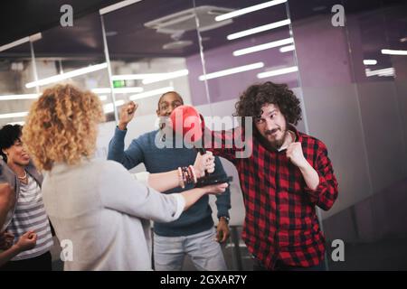 multiethnics startup business team of software developers having fun while boxing at office,excited diverse employees laughing enjoying funny activity Stock Photo