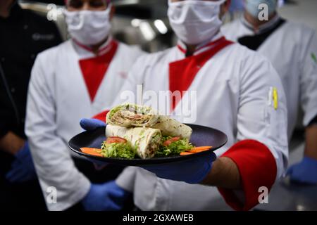 Mixed race team Portrait of group chefs standing together in the kitchen at restaurant wearing protective medical mask and gloves in coronavirus new n Stock Photo