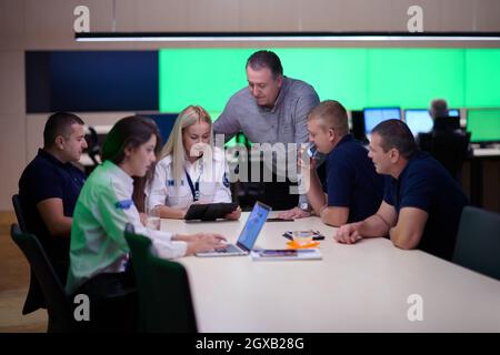 Group of security guards sitting and having briefing In the system control room  They're working in security data center surrounded by multiple Screen Stock Photo
