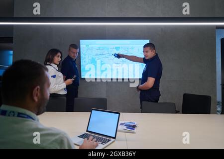 Group of Security data center operators working in a CCTV monitoring room looking on multiple monitors  Officers Monitoring Multiple Screens for Suspi Stock Photo