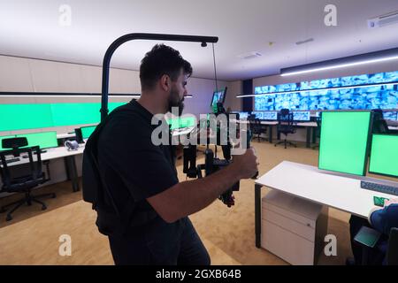 Professional videographer with gimball video slr recording video of Security data center operators while working in a CCTV monitoring room looking on Stock Photo