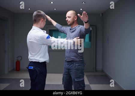 Security Guard Making Body Searching Procedure With A Metal Detector On ...