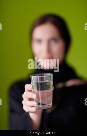 Modern Muslim Woman in Abaya Holding a Date Fruit and glass of water in from of her. Concept celebration of iftar in ramadan and end of feasting Stock Photo