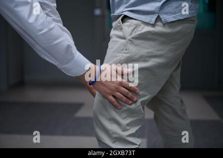 Security guard making body searching procedure on man for finding hidden objects before entering in treasury department Stock Photo