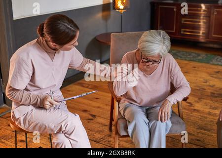 Portrait of young woman comforting crying senior lady during therapy session at retirement home, copy space Stock Photo