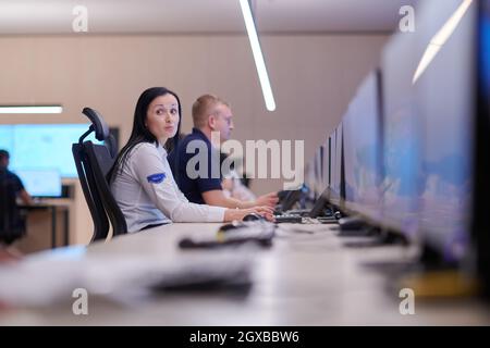 Female security operator working in a data system control room offices Technical Operator Working at  workstation with multiple displays, security gua Stock Photo