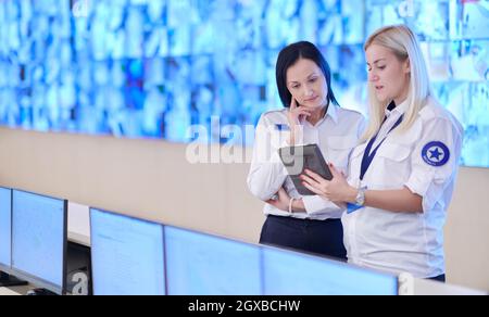 group of female security operators working in a data system control room  Technical Operators Working at  workstation with multiple displays, security Stock Photo