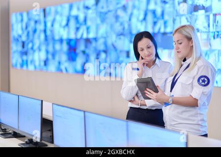 group of female security operators working in a data system control room  Technical Operators Working at  workstation with multiple displays, security Stock Photo
