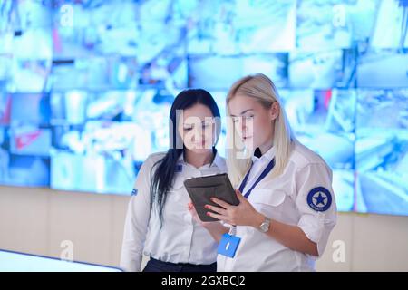 group of female security operators working in a data system control room  Technical Operators Working at  workstation with multiple displays, security Stock Photo