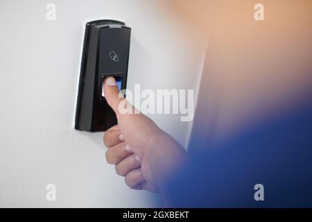 man pressing fingerprint scanner on alarm system indoors Finger print scan for unlock door security system Stock Photo