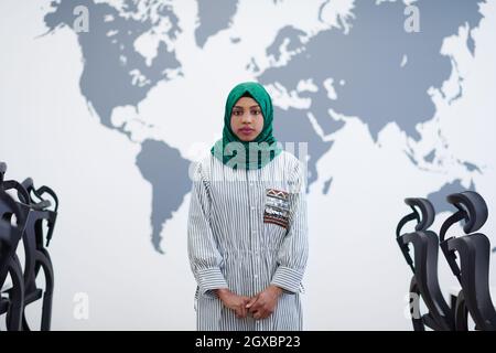 Portrait of muslim african female software developer with green hijab standing at modern open plan startup office Stock Photo