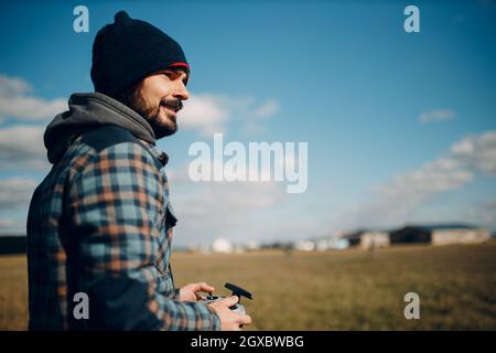 Man pilot controlling quadcopter drone with remote controller pad. Stock Photo