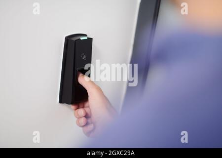 man pressing fingerprint scanner on alarm system indoors Finger print scan for unlock door security system Stock Photo