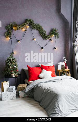 Cozy bedroom. Bed in interior of room. Scandinavian interior with christmas tree, real photo. Hygge decoration. Christmas concept Stock Photo