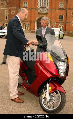 Prince Charles, Prince of Wales examines a Vectrix electric eco-friendly scooter with Alex Bamberg of Vectrix UK during a test drive around the car park of the Hampton Court Palace on June 4, 2007. The Royal test drive took place ahead of the Brighton to London Eco-Car Rally tomorrow. Stock Photo