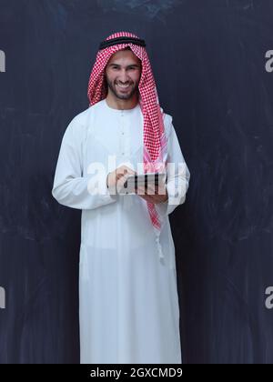 young arabian muslim businessman using tablet computer wearing hijab clothes in front of black chalkboard Stock Photo