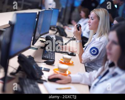 group of female security operators working in a data system control room  Technical Operators Working at  workstation with multiple displays, security Stock Photo