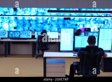 Male security operator working in a data system control room offices Technical Operator Working at  workstation with multiple displays, security guard Stock Photo