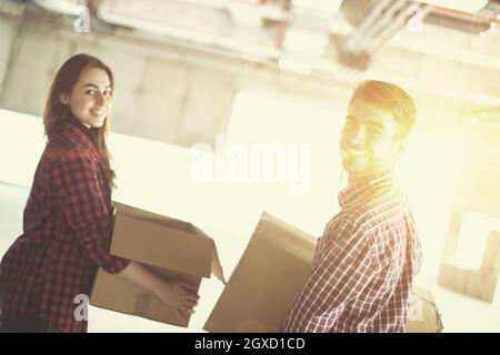 happy young casual business team carrying cardboard boxes with sunlight through the windows during moving in at new unfinished startup office building Stock Photo