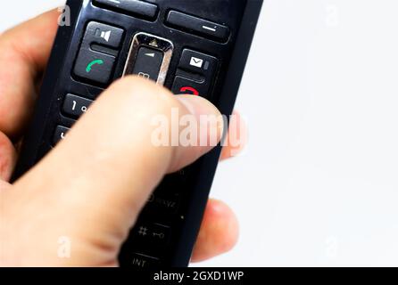 Thumb pushing the button with the red icon to reject or hang up a call on the phone. Landline telephony. Wireless phone. Stock Photo
