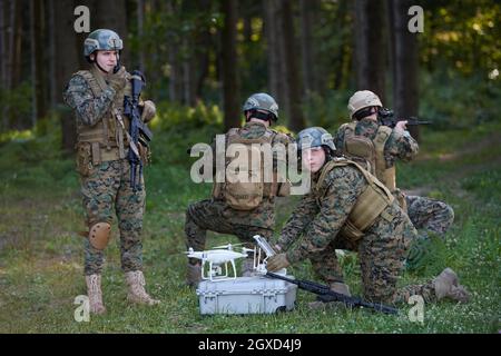 Modern Warfare Soldiers Squad are Using Drone for Scouting and Surveillance During Military Operation in the Forest. Stock Photo
