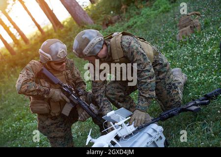 Modern Warfare Soldiers Squad are Using Drone for Scouting and Surveillance During Military Operation in the Forest. Stock Photo