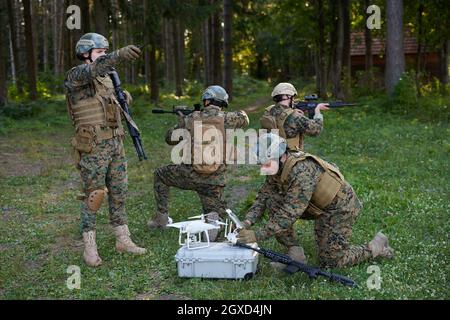Modern Warfare Soldiers Squad are Using Drone for Scouting and Surveillance During Military Operation in the Forest. Stock Photo