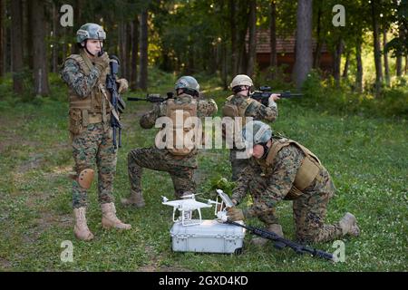 Modern Warfare Soldiers Squad are Using Drone for Scouting and Surveillance During Military Operation in the Forest. Stock Photo