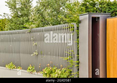 Smiling young African American female listening to music through wireless headphones while standing against contemporary urban building on city street Stock Photo