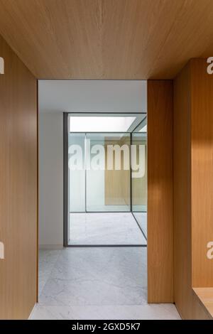 Minimalist interior of spacious corridor with wooden and glass walls and marble tiled floor in sunlight Stock Photo