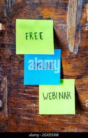 Colorful sticky notes on wooden board reminder. Free webinar written sticker on pineboard. Register for free online webinar workshop business concept. Stock Photo
