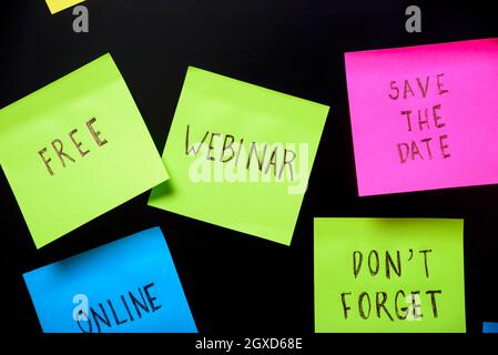 Colorful sticky notes on black board reminder. Free webinar written sticker on pineboard. Register for free online webinar workshop business concept. Stock Photo
