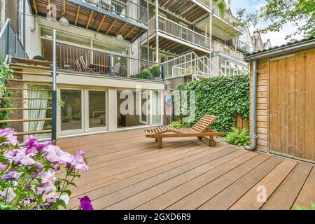 Wooden sunbed placed on terrace near huge mansion on summer day in countryside Stock Photo
