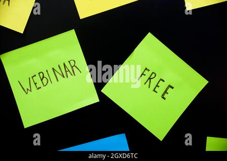 Colorful sticky notes on black board reminder. Free webinar written sticker on pineboard. Register for free online webinar workshop business concept. Stock Photo