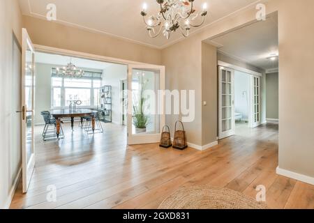 Interior of contemporary spacious apartment with hallway and dining room with table and chairs near window Stock Photo