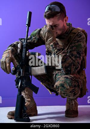 sad soldier has psychological problems holding his head in a squatting position Stock Photo