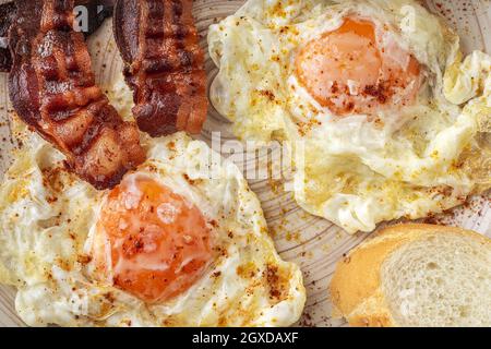 Tasty sunny side up eggs with fried bacon strips on plate Stock Photo