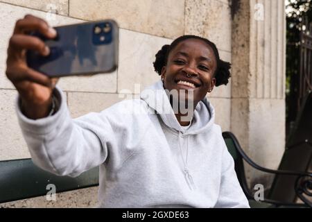 Smiling African American female with piercing taking self portrait with smartphone Stock Photo